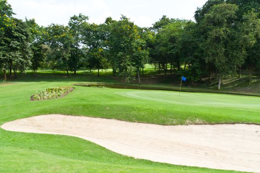 The golf course, grass and sand on blue sky.