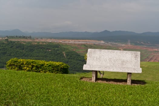 Cement bench on green grass and sky background