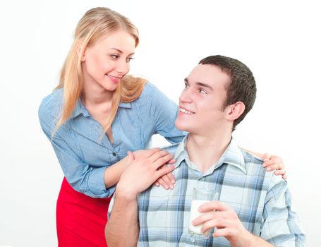 wife embraces the husband, he holds a glass of milk