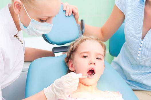 female dentists examines a child, my mother was sitting beside him and soothes baby