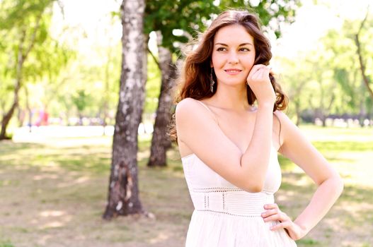 Portrait of an attractive woman in the park, her hair and smiling