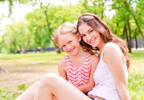 mother and daughter sitting together on the grass, and spend time with family