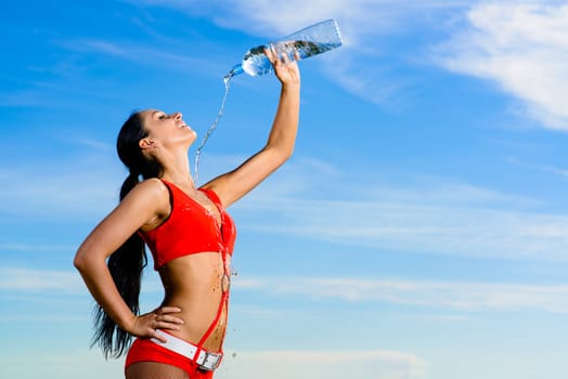 Young female sport girl in red uniform with a bottle of water
