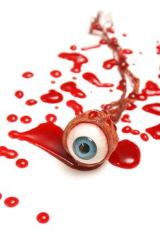 A realistic looking eyeball in a pool of blood over a white background.