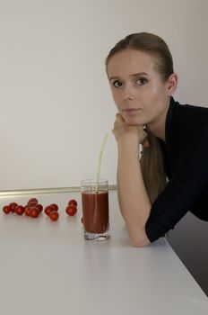 girl with a glass of tomato juice and cherry tomatoes leaning on a table