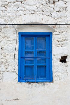 Old blue wooden window on whitewashed stone wall in Turkey.