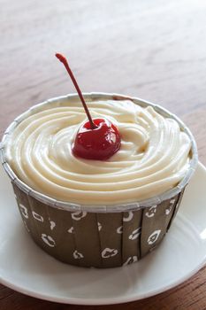 Cupcake with red cherry on white plate