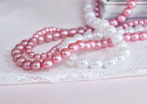 White and pink pearl necklace on top of books