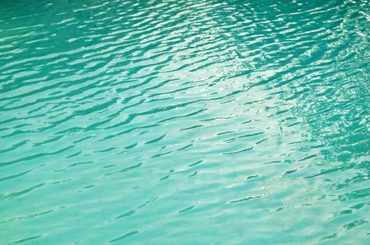 Sun reflecting on ripples of green pool water
