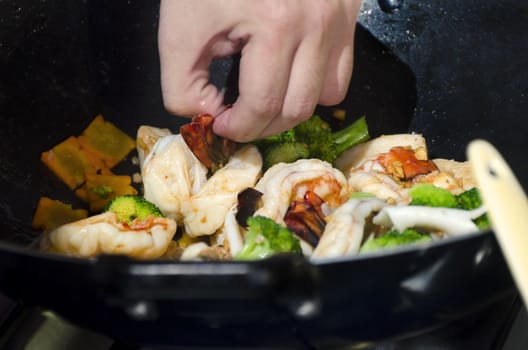 Close-up of shrimps and vegetables in wok with wooden spoon