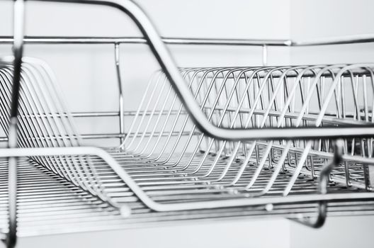 Close-up of stainless steel dish rack inside kitchen cabinet