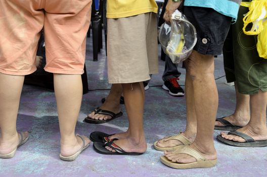 Matured women wearing mostly slippers and shorts standing in line
