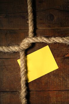 Blank yellow paper attached to wooden surface with rope