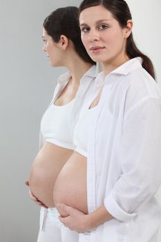 A pregnant woman standing in front of a mirror.