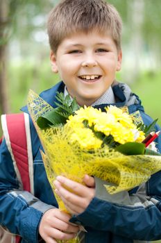 Schoolboy with a bouquet of yellow chrysanthemums in the park