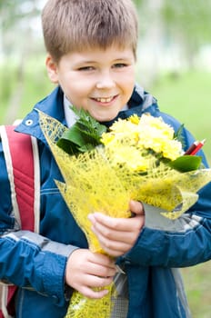 Schoolboy with a bouquet of yellow chrysanthemums in the park