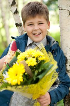 Schoolboy with a bouquet of yellow chrysanthemums in the park