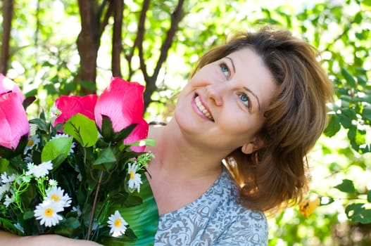 woman with a bouquet of artificial flowers in summer park