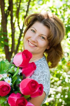 woman with a bouquet of artificial flowers in summer park