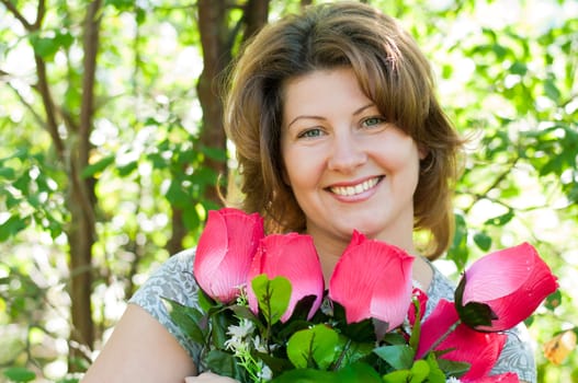 woman with a bouquet of artificial flowers in summer park