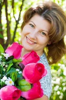 woman with a bouquet of artificial flowers in summer park
