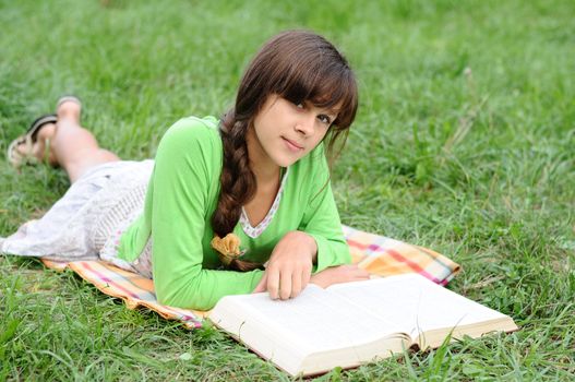 Girl reading a book lying on the grass