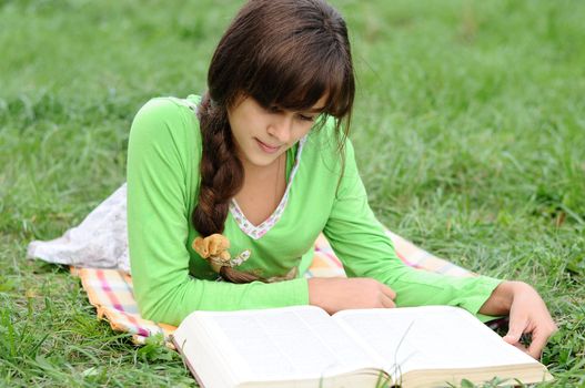 Girl reading a book lying on the grass