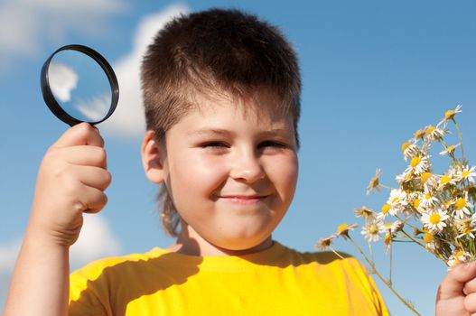 Boy sees flowers through magnifying glass