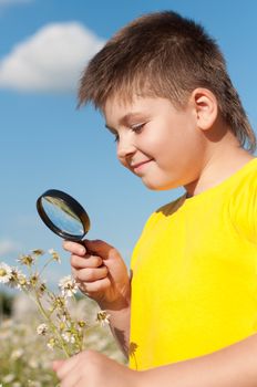 Boy sees flowers through magnifying glass