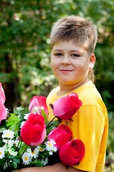 A boy with a bouquet of artificial flowers in summer park