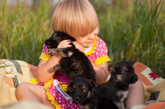 Little girl playing with puppies