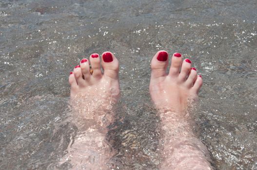 Female feet on a background of sea water