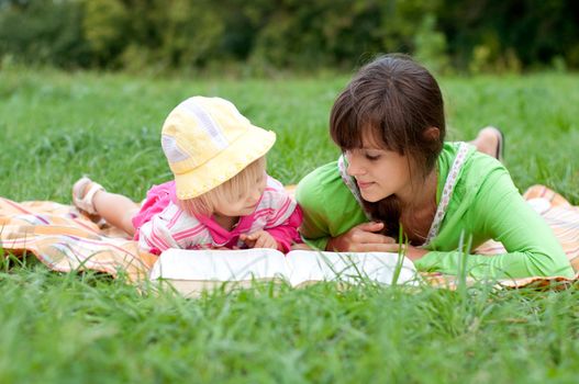 Two sisters reading a book outdoors