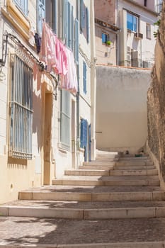 A part of the street with steps and hanged out clothes from the window on a sunny day