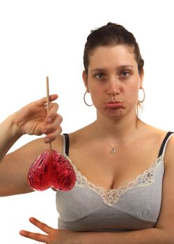 Sad young woman hold heart shaped lollipop upside down after a breakup