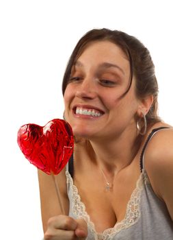 Young woman looks at heart shaped lollipop, isolated over white