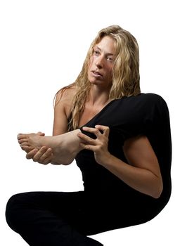 Flexible blond woman stretches with leg above shoulder, isolated over white