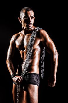 Bodybuilder with chains in dark