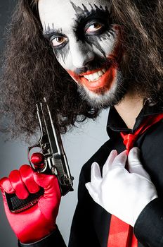 Evil clown with gun in dark room