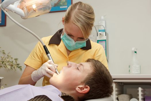 dentist treats the boy's teeth with a drill