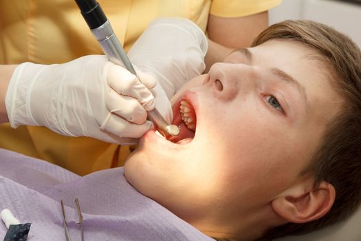 dentist treats the boy's teeth with a drill