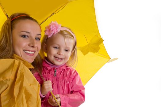 Mother and baby daughter under yellow umbrella on white