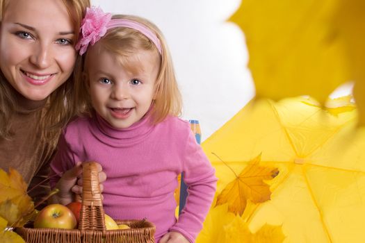 Mother and little daughter with basket and falling yellow leaves