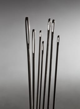 Row of sewing embroidery needles against grey background