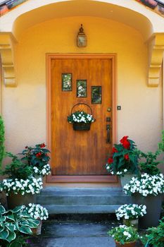 Weathered wood stained home door with three windows and flowers
