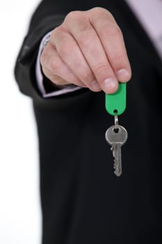 A cropped picture of a businessman handing a key.
