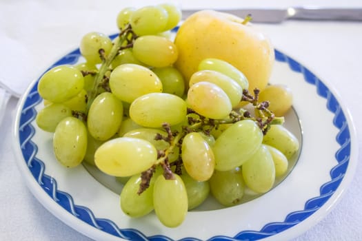 Sweet green grapes and apple served on a plate