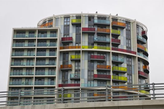 An abstract architectural apartment building made of one part square, one part round, with numerous colourful balconies with copy space.