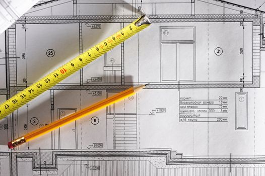 Pencil and tape meausure over house plan blueprints