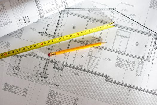 Pencil and tape meausure over house plan blueprints